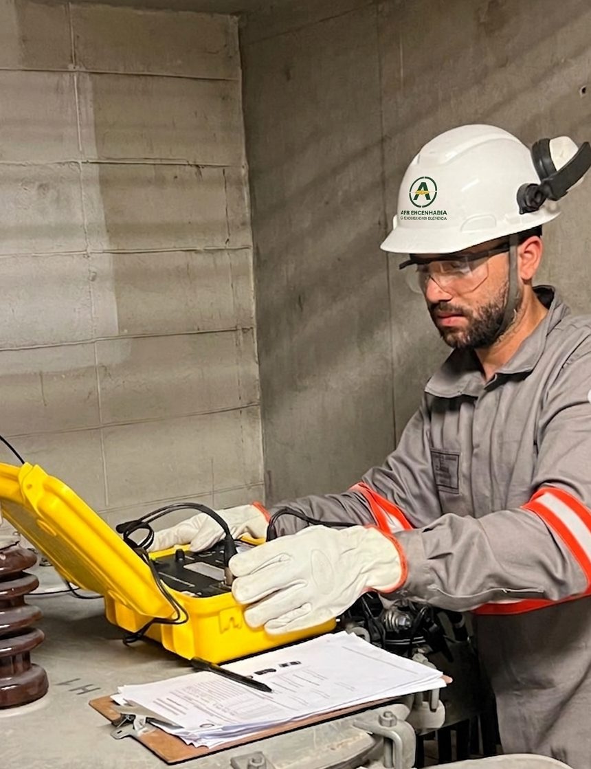 Arthur Felipe Brandão, engenheiro eletricista da AFB, de capacete, óculos e luvas, realizando ensaio com instrumento sobre um transformador